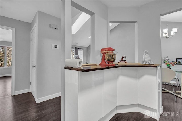 interior space featuring a chandelier, baseboards, pendant lighting, and dark wood finished floors