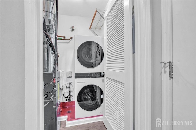 laundry room with dark hardwood / wood-style floors and stacked washer and dryer