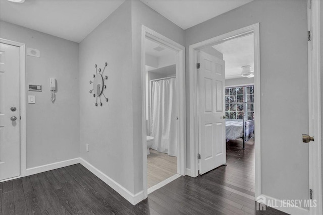 corridor featuring dark wood-type flooring and baseboards