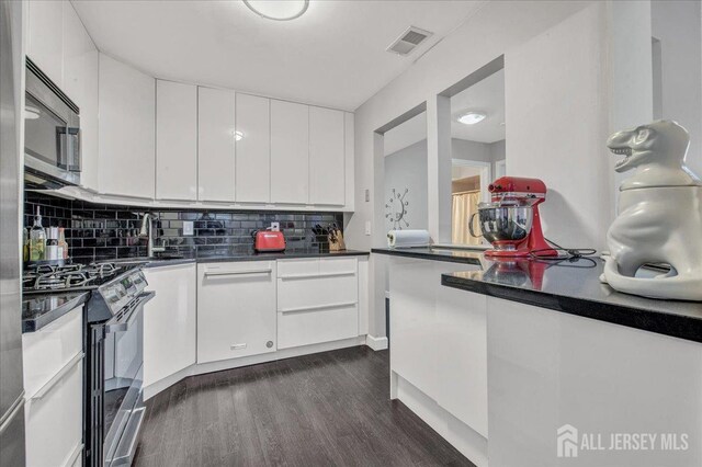 kitchen featuring sink, white cabinetry, tasteful backsplash, dark hardwood / wood-style flooring, and appliances with stainless steel finishes