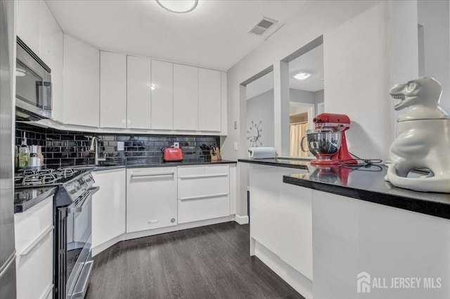 kitchen featuring visible vents, backsplash, dark wood-style floors, appliances with stainless steel finishes, and white cabinets