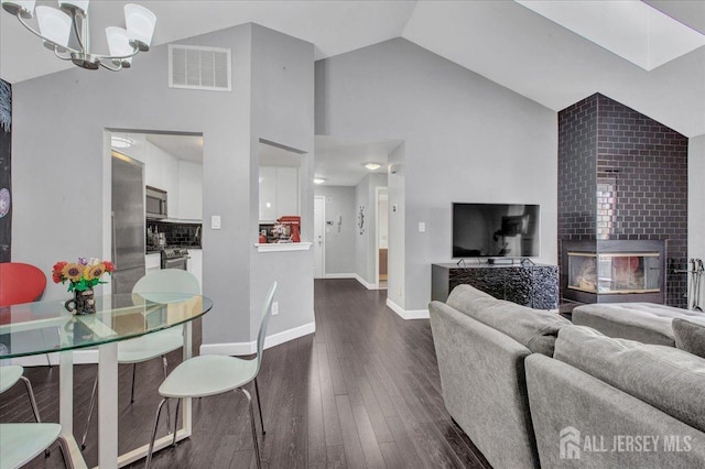 living room featuring baseboards, visible vents, lofted ceiling, dark wood-type flooring, and a notable chandelier