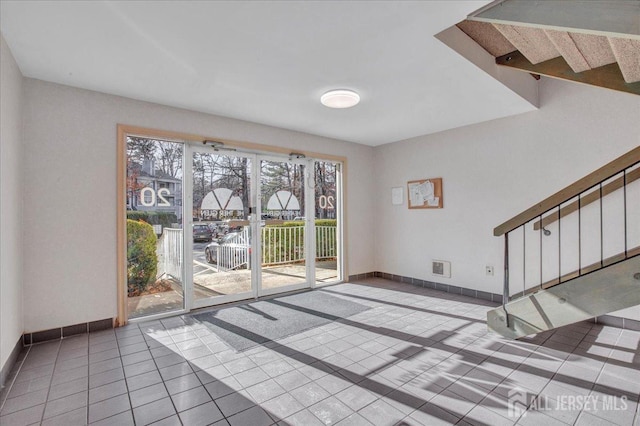 interior space featuring tile patterned flooring, visible vents, stairs, and baseboards