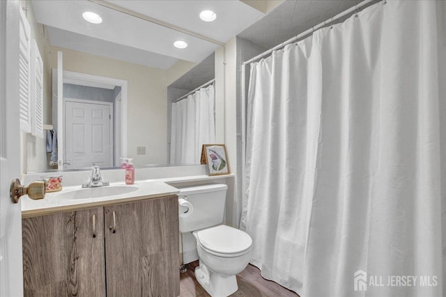 bathroom with recessed lighting, toilet, wood finished floors, and vanity