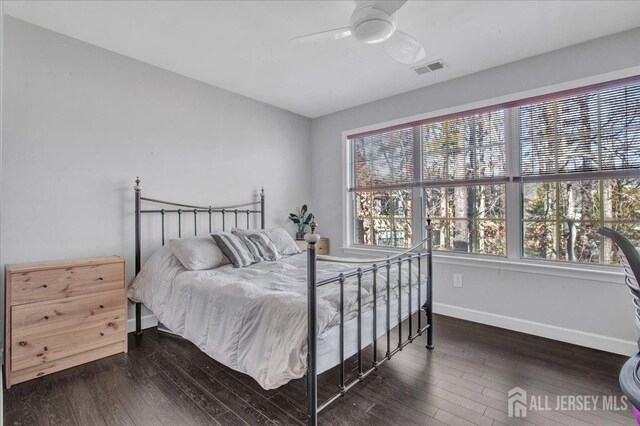 bedroom with ceiling fan, dark wood-type flooring, and multiple windows