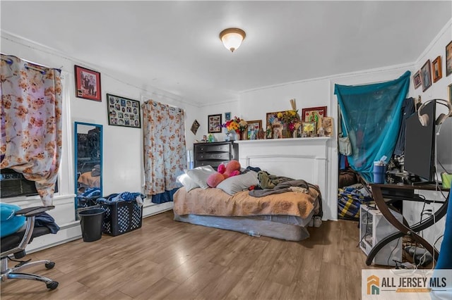 bedroom featuring crown molding, cooling unit, wood finished floors, and baseboard heating