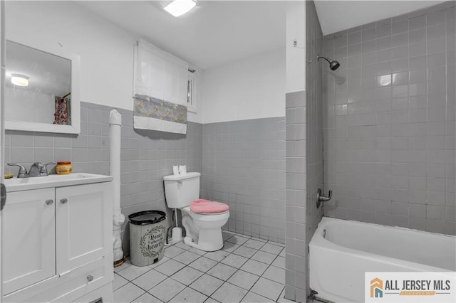 bathroom featuring toilet, tile walls, shower / washtub combination, and tile patterned flooring