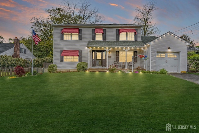 view of front of property featuring a porch, a garage, and a lawn