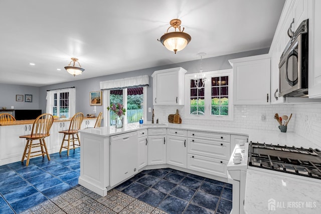 kitchen with white appliances, hanging light fixtures, backsplash, white cabinets, and kitchen peninsula