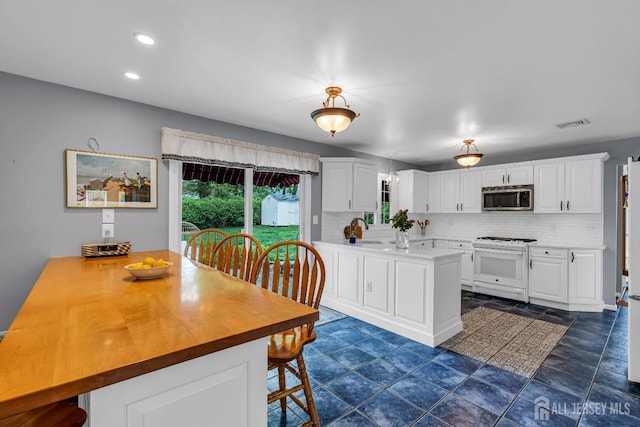 kitchen featuring white gas range, kitchen peninsula, and white cabinets