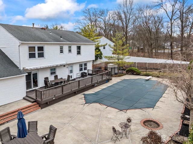 view of swimming pool with a fenced in pool, a fire pit, fence, a wooden deck, and outdoor dining space