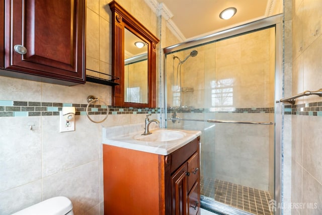 bathroom with vanity, a shower stall, toilet, and tile walls