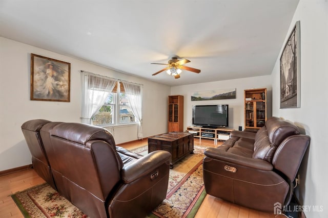 living room with baseboards, light wood-type flooring, and ceiling fan