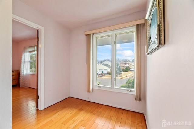 spare room featuring light wood-type flooring and baseboards