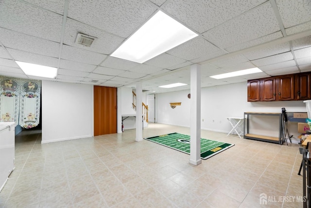 finished below grade area featuring a paneled ceiling, visible vents, and baseboards