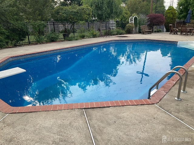 view of swimming pool featuring a diving board, a fenced in pool, fence, and a patio area