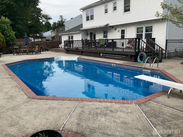 view of pool featuring a deck, fence, a diving board, a fenced in pool, and a patio area