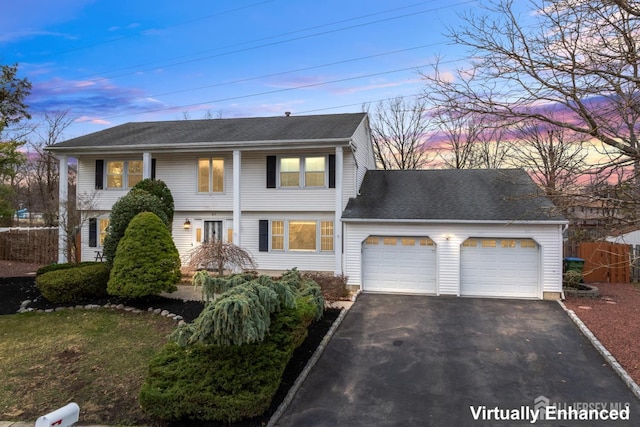 colonial home with driveway, roof with shingles, and an attached garage