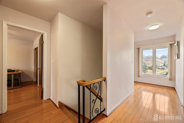 hallway featuring an upstairs landing, light wood finished floors, and baseboards