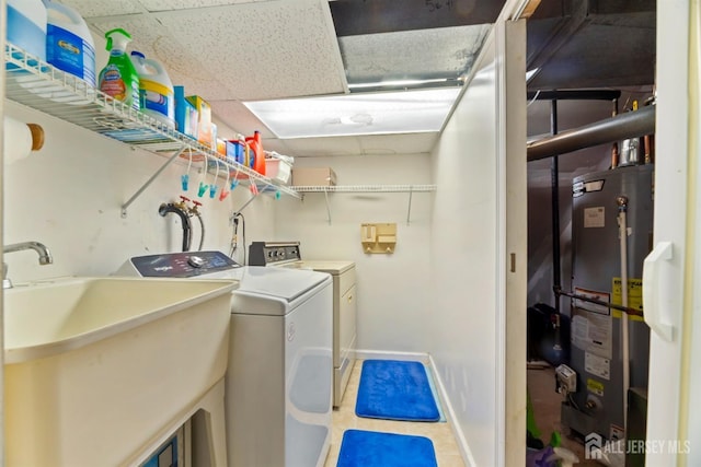 laundry room featuring tile patterned flooring, baseboards, water heater, laundry area, and a sink