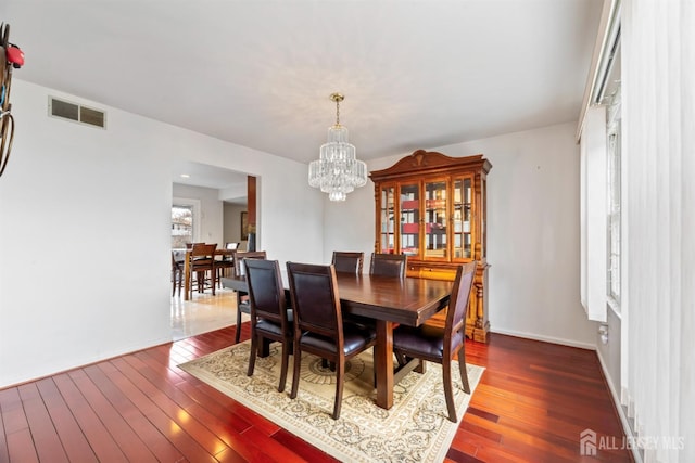 dining area featuring dark wood finished floors, baseboards, visible vents, and a chandelier