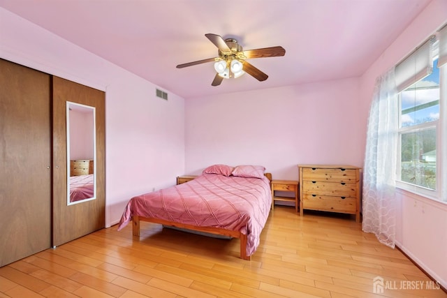 bedroom with a closet, visible vents, a ceiling fan, and light wood-style floors