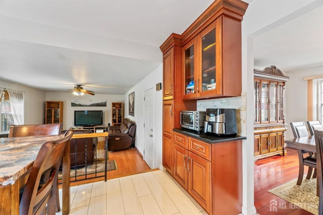 kitchen featuring brown cabinetry, a healthy amount of sunlight, light wood-type flooring, and ceiling fan