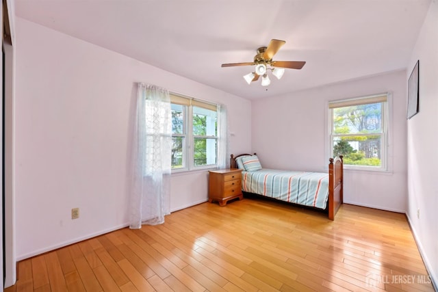 unfurnished bedroom featuring light wood-style flooring, multiple windows, and a ceiling fan