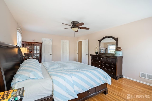 bedroom with a ceiling fan, visible vents, light wood-style flooring, and baseboards