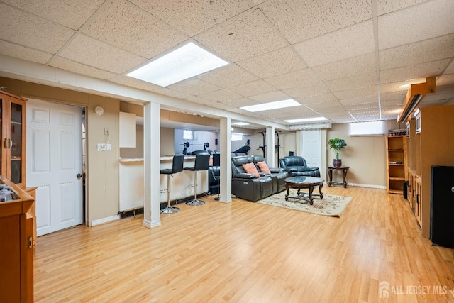 living area featuring a drop ceiling, baseboards, and wood finished floors