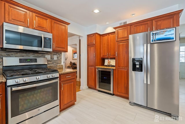 kitchen featuring beverage cooler, tasteful backsplash, appliances with stainless steel finishes, and light stone countertops