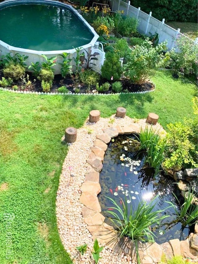 view of yard with a fenced in pool, fence, and a garden pond