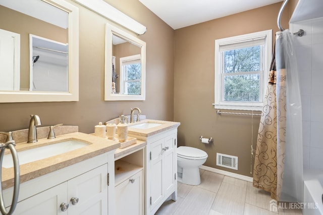 bathroom with visible vents, a sink, baseboards, and double vanity