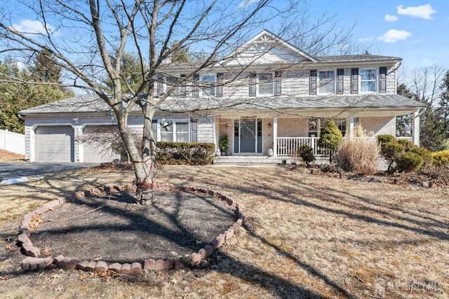 view of front facade with a garage, covered porch, aphalt driveway, and brick siding