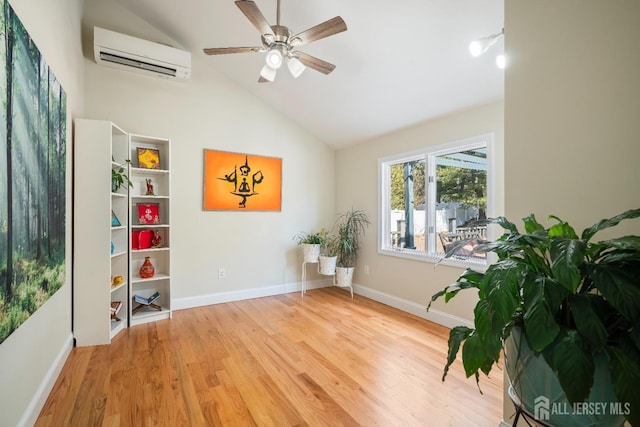 living area with a wall mounted AC, a ceiling fan, vaulted ceiling, wood finished floors, and baseboards