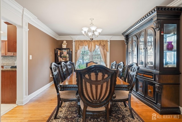 dining space with ornamental molding, light wood-style flooring, baseboards, and an inviting chandelier