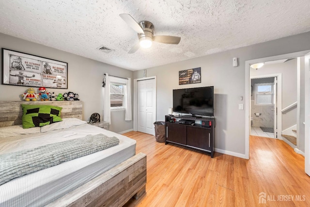 bedroom with light wood-type flooring, a textured ceiling, ceiling fan, and a closet