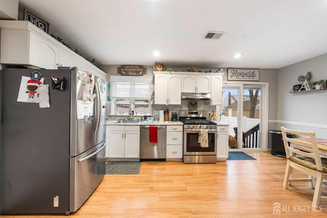 kitchen with stainless steel appliances, sink, light hardwood / wood-style floors, and white cabinets