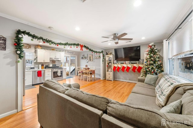 living room with ornamental molding, a wealth of natural light, ceiling fan, and light hardwood / wood-style flooring