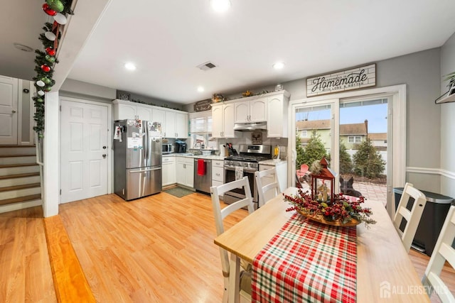 kitchen featuring stainless steel appliances, light hardwood / wood-style floors, decorative backsplash, and white cabinets