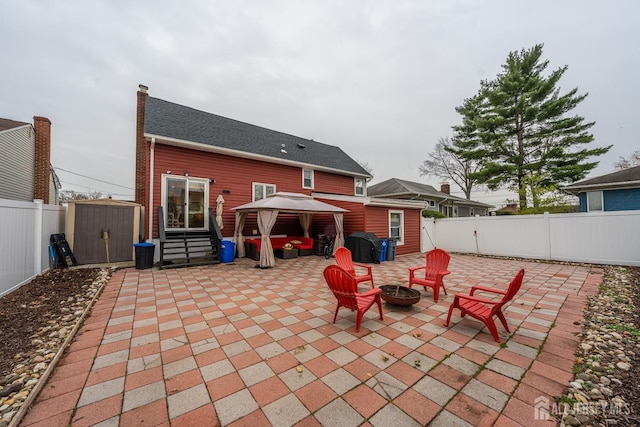 rear view of house featuring a storage shed, an outdoor fire pit, a patio area, and a gazebo