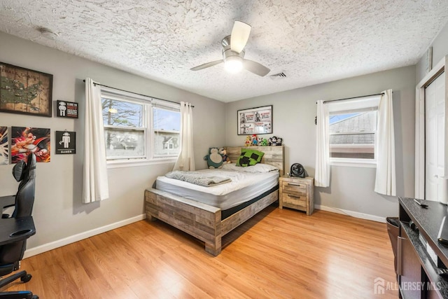 bedroom with a textured ceiling, ceiling fan, and light wood-type flooring