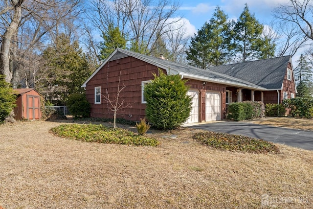 view of home's exterior featuring aphalt driveway, an outdoor structure, an attached garage, and a shed