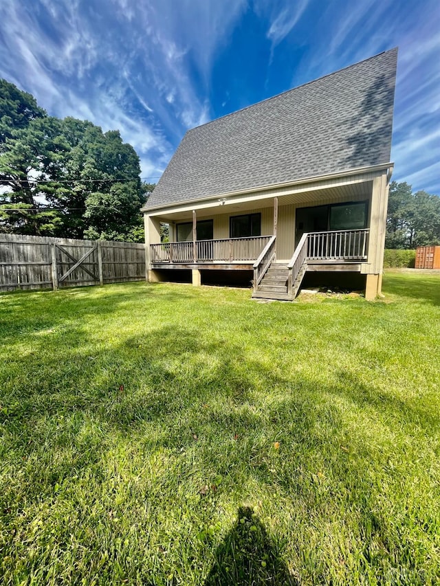 rear view of property featuring a wooden deck and a lawn