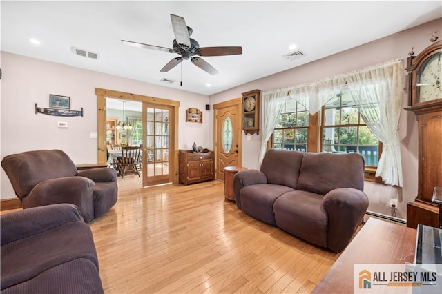 living room featuring a ceiling fan, light wood finished floors, baseboard heating, and recessed lighting