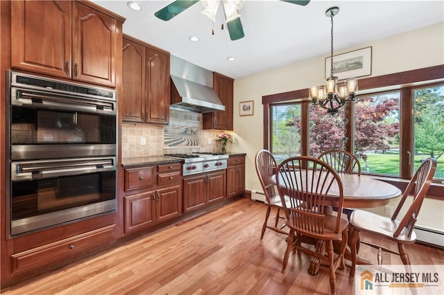kitchen with wall chimney range hood, appliances with stainless steel finishes, a ceiling fan, tasteful backsplash, and light wood-type flooring