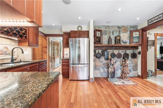 kitchen with freestanding refrigerator, a sink, tasteful backsplash, light wood-style floors, and recessed lighting