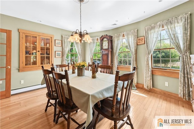 dining space featuring a baseboard radiator, a chandelier, light wood-style floors, and baseboards