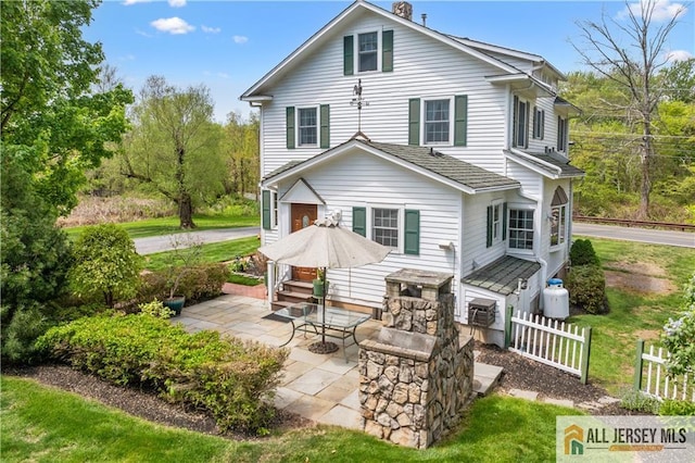 rear view of property with fence and a patio
