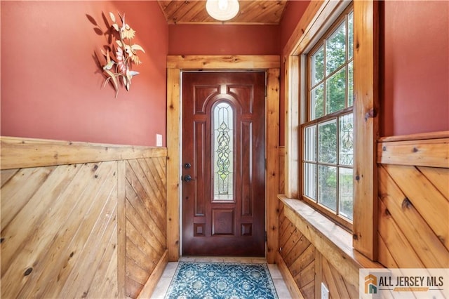 doorway featuring wood ceiling, wood walls, and wainscoting